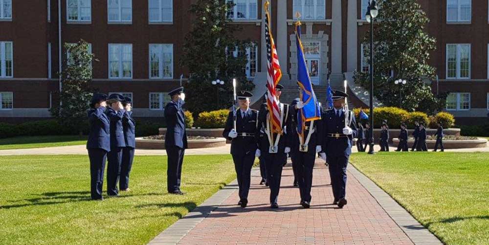 Blue Knights marching with flags on the drill field