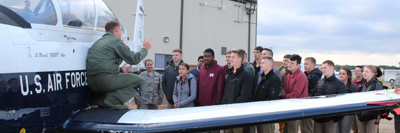 Students crowded around air plane and listening to pilot talk